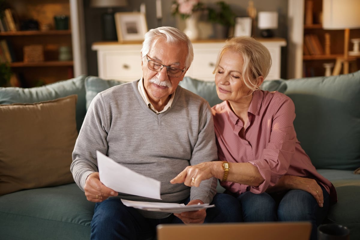 Couple reviewing life insurance policy documents together at home while planning their future finances